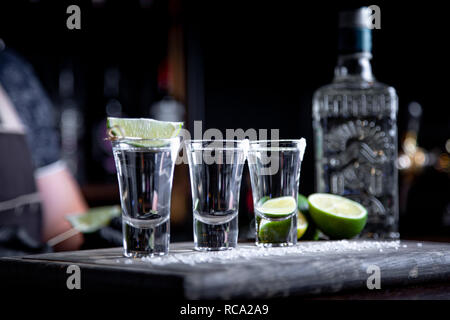 Barman versando hard spirito in piccoli bicchieri come bevande a colpi di tequila o drink forte Foto Stock