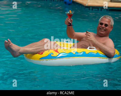 Älterer Mann genießt das Leben im Schlauchboot kleinen im Swimmingpool | uomo anziano con un gommone in piscina Foto Stock