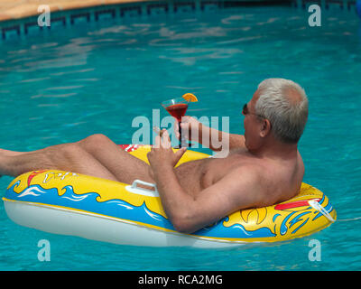 Älterer Mann genießt das Leben im Schlauchboot kleinen im Swimmingpool | uomo anziano con un gommone in piscina Foto Stock