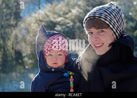 Mutter mit Baby im braccio, draußen inverno | madre che porta il suo bambino in braccio, al di fuori di inverno Foto Stock