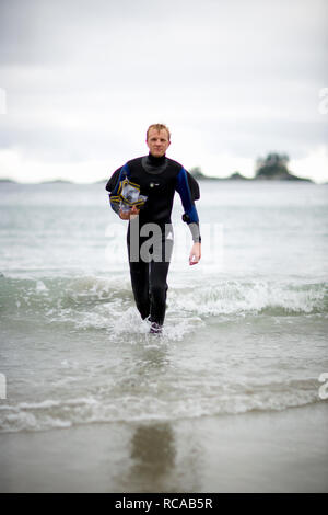 Ritratto di una metà di uomo adulto che indossa una muta umida mentre proveniente dal mare. Foto Stock