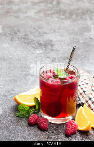 Frutta rossa tè con lampone e arancia sul tavolo grigio Foto Stock