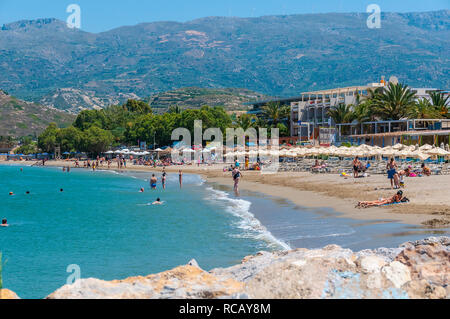 Turisti e residenti per godersi la spiaggia in un caldo giorno d'estate a Sitia in orientale di Creta, Grecia Foto Stock