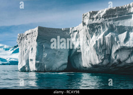 Close-up iceberg soleggiato. Antartide di scena in blu e bianco tinte. Incredibile coperta di neve blocco di ghiaccio con ghiaccioli floating tra l'oceano polare. Il cielo nuvoloso sfondo. Il pittoresco paesaggio invernale. Foto Stock