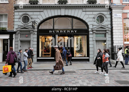 Persone acquirenti e uomo portare borsa a piedi oltre Burberry negozio esterno a Natale a Covent Garden Londra Inghilterra Regno Unito KATHY DEWITT Foto Stock