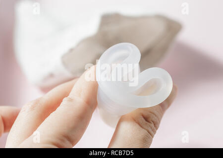Stretta di mano donna piegatura coppa mestruale che mostra come utilizzare, c formano. Salute della donna concetto, rifiuti zero alternative Foto Stock