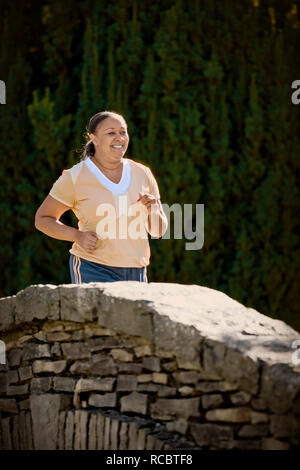 Metà donna adulta che corre lungo un parco. Foto Stock