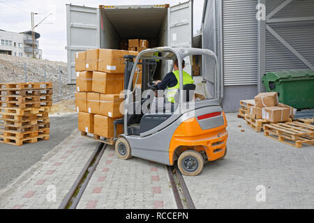 Scatole di carico presso il pallet con un carrello elevatore in contenitore di carico in treno Foto Stock