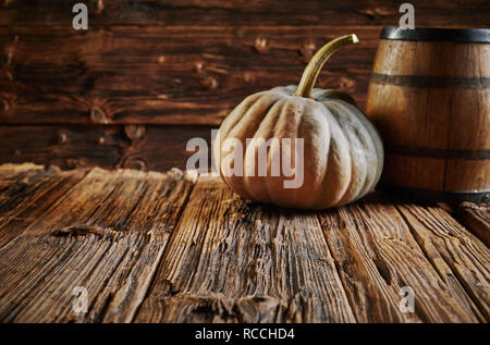 Grande zucca e botte di rovere in casa di legno camera sulla tabella con il vecchio dure woodgrain superficie. Rustico concetto raccolto in marrone con spazio di copia Foto Stock