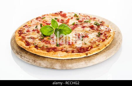 Vista laterale del pane appena sfornato pizza Margherita servita sul round tagliere di legno su sfondo bianco Foto Stock