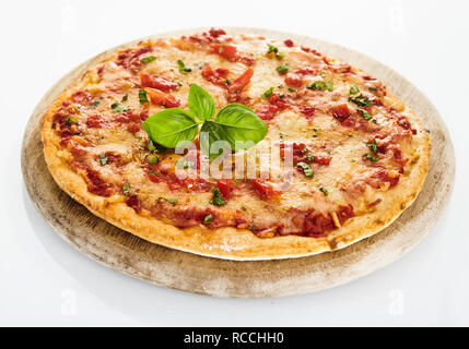 Pomodoro italiano pizza Margherita con foglie fresche di basilico, servito sul round tagliere di legno, visto da vicino da un angolo alto, isolato su bianco Foto Stock