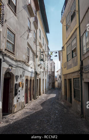 Un vialetto in ciottoli che conducono in basso tra i tipici edifici con il fado bar e parete e appeso street decorazioni in Coimbra Portogallo Foto Stock