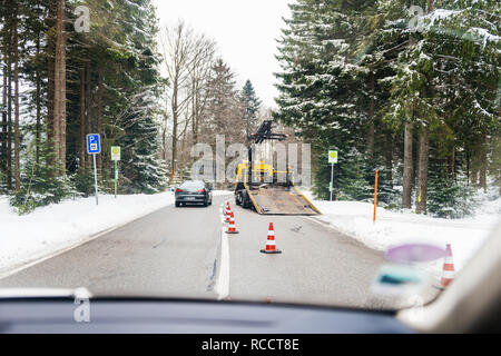 BADEN WURTTEMBERG, Germania - 25 FEB 2018: Driver punto di vista sulla sicurezza di lavoro di sicurezza per il traino carrello auto dall'ADAC auto aiutando durante l'incidente nella foresta strada innevata. L'ADAC è l'abbreviazione di Allgemeiner Deutscher Automobil-Club tradotto Foto Stock