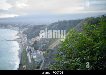 Giardini Naxos con un albero in primo piano, come visto da Taormina, Sicilia, Italia Foto Stock