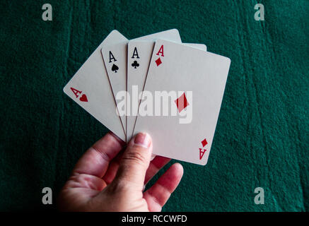 Una persona che gioca a poker con i quattro assi di un mazzo di carte in mano Foto Stock