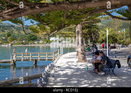 Akaroa, Nuova Zelanda, 6 Gennaio 2019: il turista a godere la vista della baia in una calda serata estiva Foto Stock