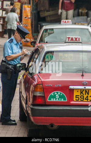 Isola di Hong Kong, Cina - 12 Maggio 2010: un semaforo in blu scrive un rosso con taxi fino ad una infrazione di vicino a Stanley Market. Sbiadita negozi e fornitori Foto Stock