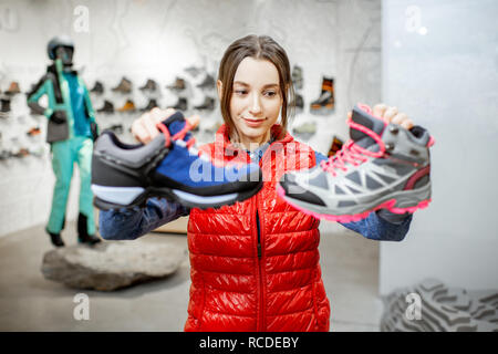 Giovane donna scegliendo trail scarpe da trekking in montagna nel moderno negozio di articoli sportivi Foto Stock