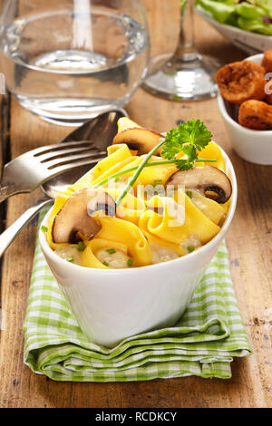 Funghi alla griglia su un piatto di pasta con salsa cremosa guarnita con erbe aromatiche servita in una elegante imbarcazione piatto sagomato per un gustoso antipasto italiano Foto Stock