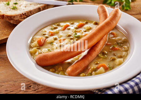 Ciotola di zuppa di piselli con due salsicce bockwurst servita sulla parte superiore in un concetto di regionale cucina tedesca Foto Stock