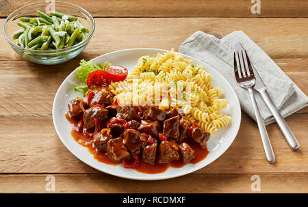 Gulasch/Spezzatino di cervo o stufato con dadini di cinghiale e capriolo servita con pasta e fagiolini freschi Foto Stock