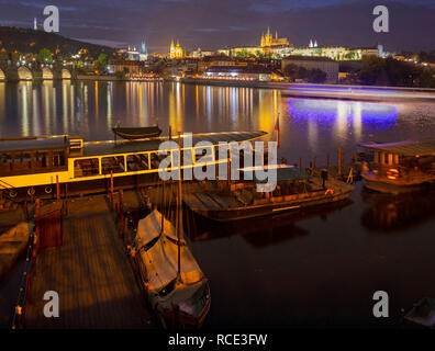 Praga - Ponte Carlo, il castello e la cattedrale con il piccolo porto al tramonto. Foto Stock