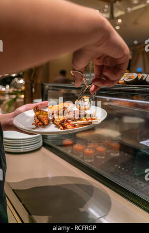 Giovane uomo scegliendo il cibo servito in albergo a buffet Foto Stock