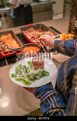 Giovane donna scegliendo il cibo servito in albergo a buffet Foto Stock