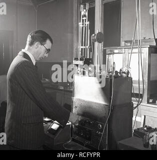 1950s, storico, all'interno di un laboratorio scientifico di ricerca, uno scienziato maschile in una tuta a a strisce utilizzando apparecchiature di test dell'epoca, Leeds University, Leeds, Inghilterra, Regno Unito Foto Stock