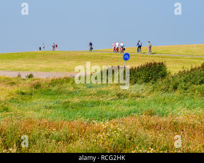 Gente in bicicletta sulla diga di barene in primo piano sulla West Frisone isola Schiermonnikoog, Paesi Bassi Foto Stock