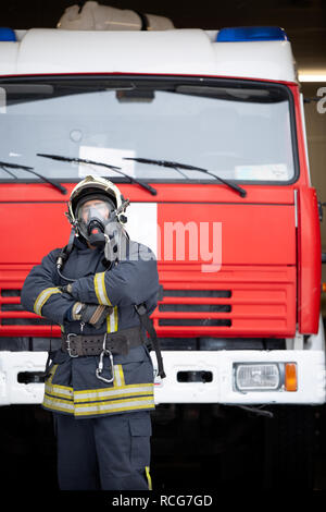 Immagine dell uomo vigile del fuoco in maschera a gas in prossimità di fuoco carrello Foto Stock