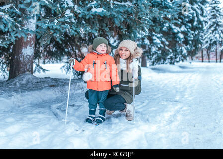 Una giovane madre insegna giovane figlio 3-5 anni di sci. In inverno nella foresta dove c è un sacco di neve. Happy amici lasciare nei fine settimana. Foto Stock