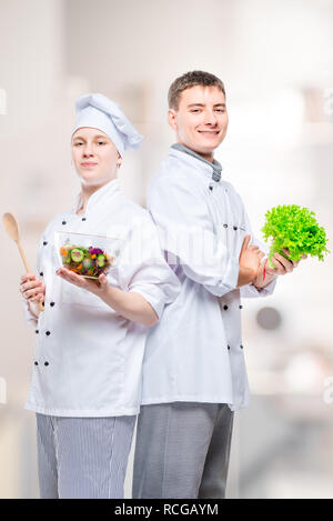 Professionale chef felice in giacca con una insalata nelle loro mani contro lo sfondo della cucina Foto Stock