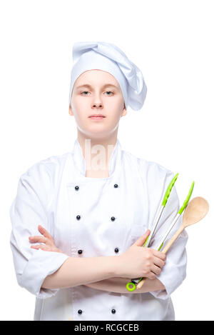 Ritratto verticale di un giovane cuoco con un cucchiaio e prelibatezze pinze isolate su sfondo bianco Foto Stock
