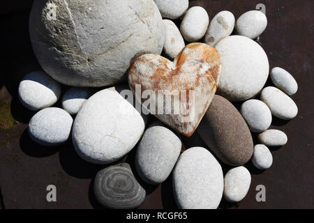 Dipinto di bianco in legno stagionato cuore raggruppati con spiaggia di ciottoli come giardino decorazione. Foto Stock