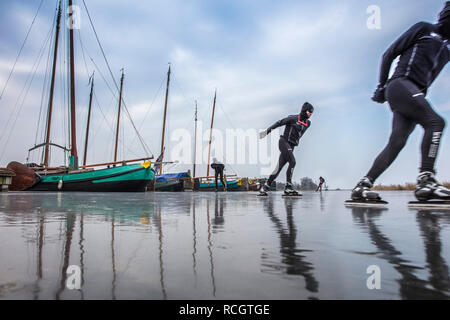 I Paesi Bassi, Sloten, pattinaggio su ghiaccio. Sfondo cargo tradizionali barche a vela. L'inverno. Foto Stock