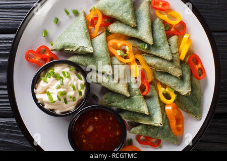 La cucina indiana spinaci samosa servita con verdure e due salse close-up su una piastra sul tavolo. parte superiore orizzontale vista da sopra Foto Stock