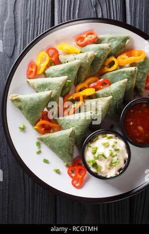 Gli spinaci vegetariana samosa con salse close-up su una piastra sul tavolo. Verticale in alto vista da sopra Foto Stock