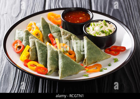 Asian spinaci samosa con pepe e due salse close-up su una piastra sul tavolo orizzontale. Foto Stock