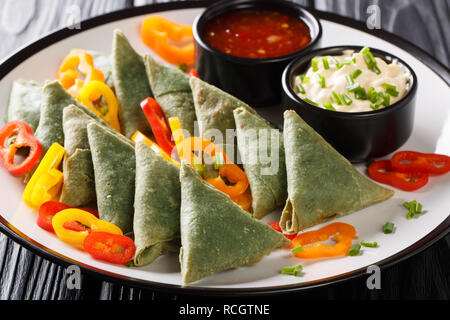 Spinacio indiano Samosa di verdure e salse close-up su una piastra sul tavolo orizzontale. Foto Stock
