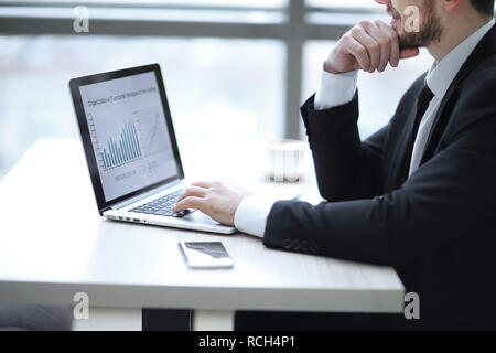 Imprenditore lavorando sul computer portatile con i dati finanziari. Foto Stock