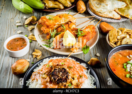 Africa occidentale il concetto di cibo. Wset tradizionali piatti africani assortimento - Zuppa di arachidi, riso jollof, grigliate di ali di pollo, secco banane fritte banane da cuocere, Foto Stock