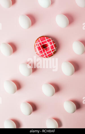 La pasqua le uova bianche ripetizione con l'ombra e la ciambella rosa rosa su sfondo color pastello, errore di sistema Foto Stock