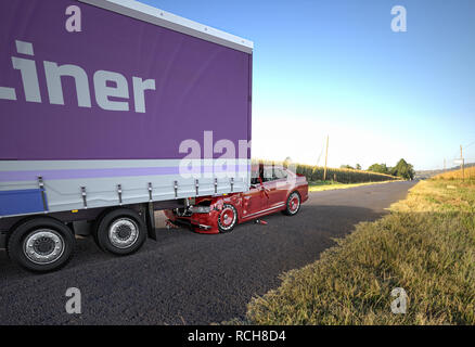 Due auto incidente. Si è schiantato vetture. Un rosso coupé/sedan contro il retro di un grosso camion. Grande danno. Sulla strada sulla posizione in campagna. Prospettiva v Foto Stock