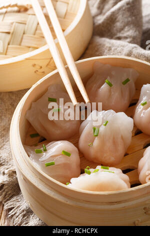 Gnocchi fatti in casa a base di dim sum con Gamberi Ripieni di close-up in un sistema per la cottura a vapore in bambù casella sulla tavola verticale. Foto Stock