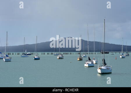 Bay con ancora acqua e ormeggiate barche a vela in legno e breakwall Rangitoto isola di Vulcano a Auckland su nuvoloso giorno. Foto Stock