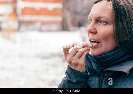 Donna applicando balsamo per labbra in fuori strada in una fredda giornata invernale Foto Stock