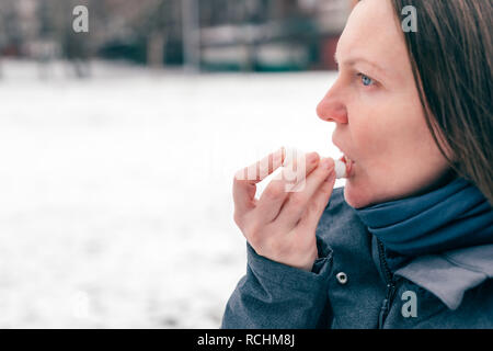 Donna applicando balsamo per labbra in fuori strada in una fredda giornata invernale Foto Stock