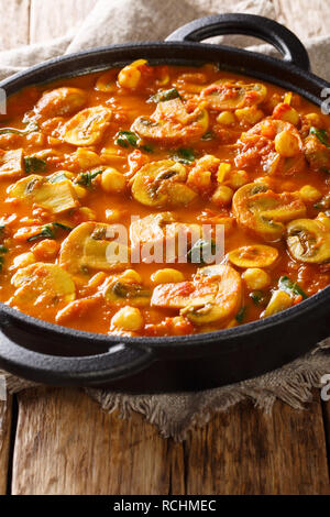 Vegetariano speziato curry di funghi con spinaci e ceci close-up in una padella sulla tavola verticale. Foto Stock