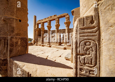 Patrimonio egiziano hyeroglyphs presso il Tempio di Philae Aswan. Focus sulle colonne del tempio in background Foto Stock